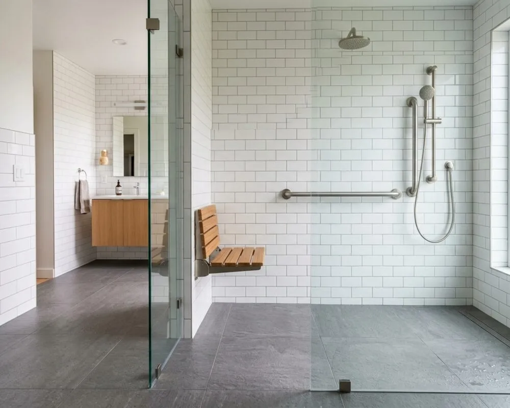 Curbless walk-in shower with a completely flat entry, fold-down teak bench, handheld sprayer on a slide bar and a grab bar
