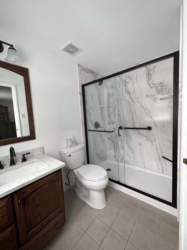 A finished bath conversion project that shows a new walk-in shower in place of an old bathtub. 