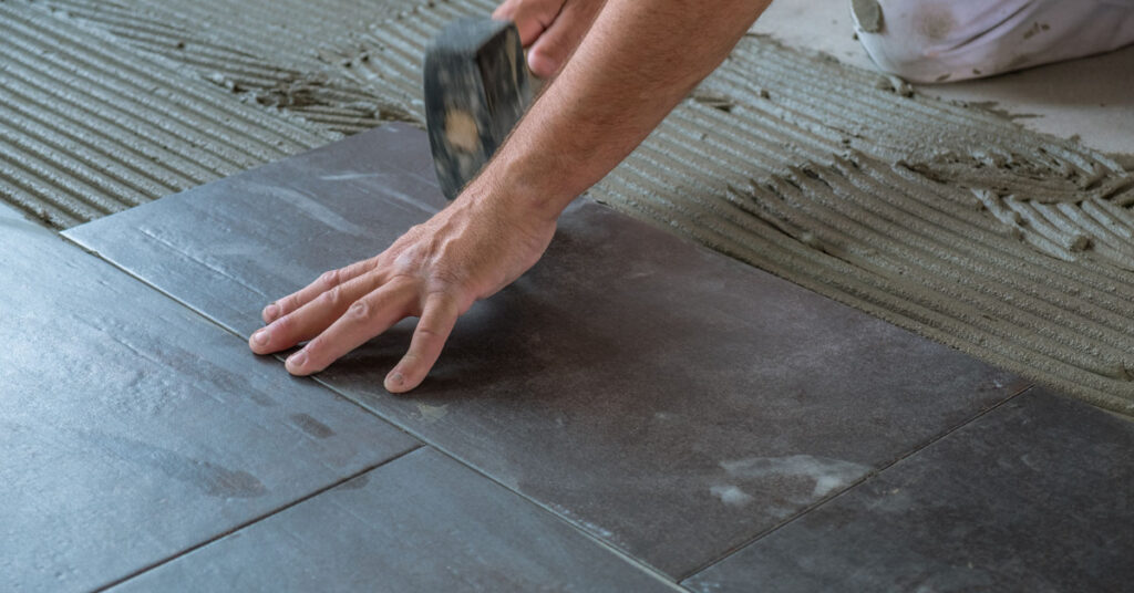 A man working on a bathroom conversions project installs a new slip-resistant floor. 