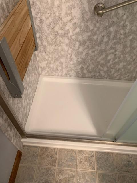 An accessible shower with grab bars and a retractable shower chair to improve accessibility were including in this bathroom conversions project from Just Bath. 