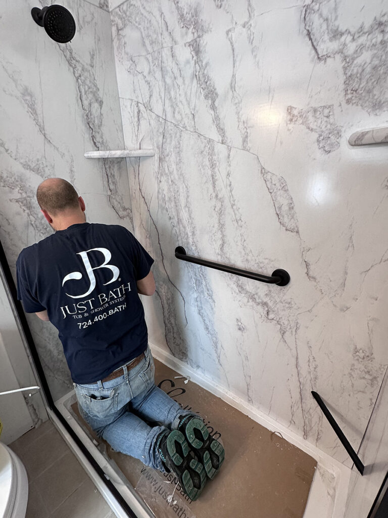 A Just Bath installer works on a bathroom conversions project installing the new finishes. 