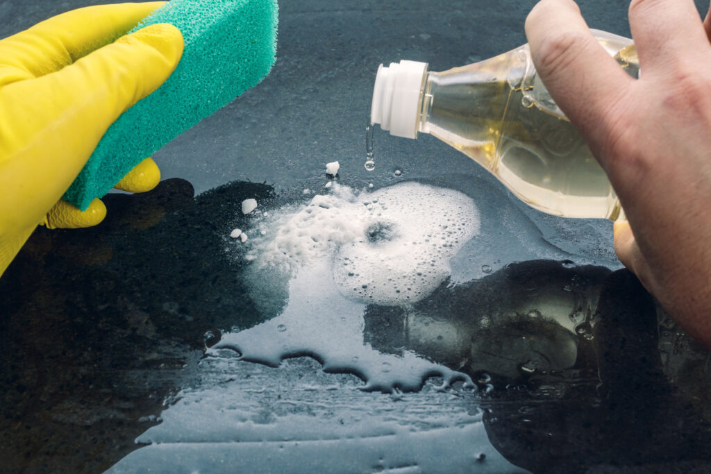 A person uses baking soda and vinegar to clean a hard surface in the bathroom as part of an eco-friendly bathroom conversion project. 